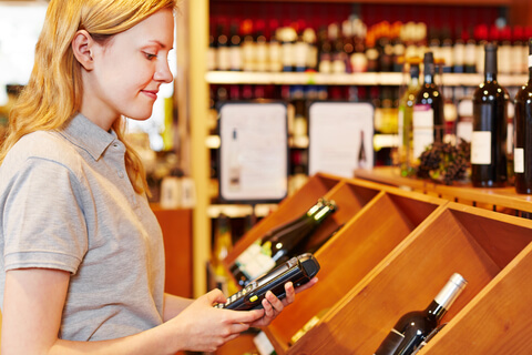 Donna che legge il codice a barre di un vino con un dispositivo mobile